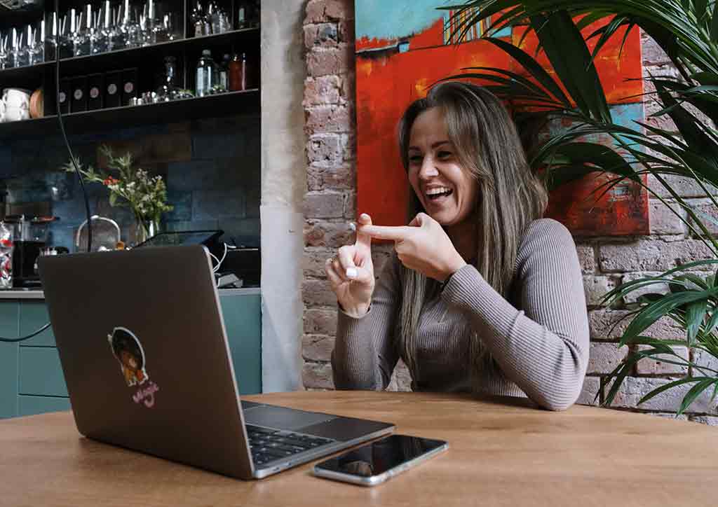 Brown-haired girl smiling at laptop screen.