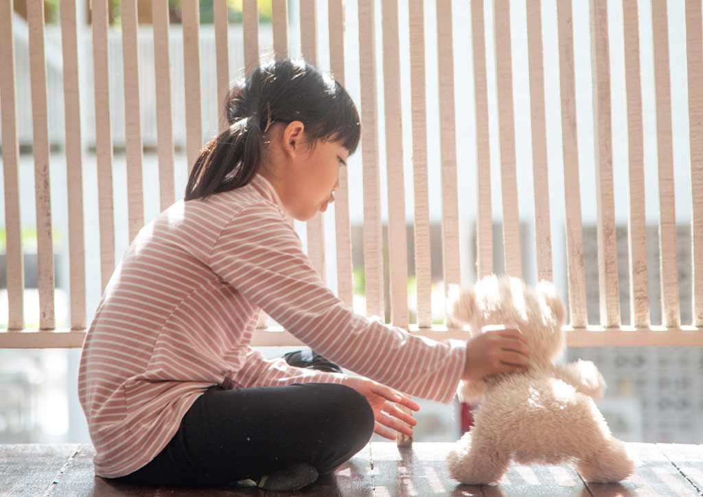 A young girl playing with her teddy bear