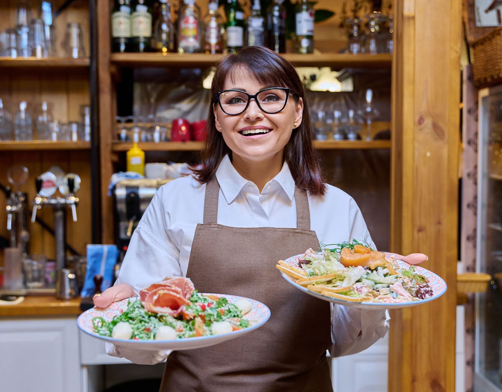 A restaurant server with two dishes