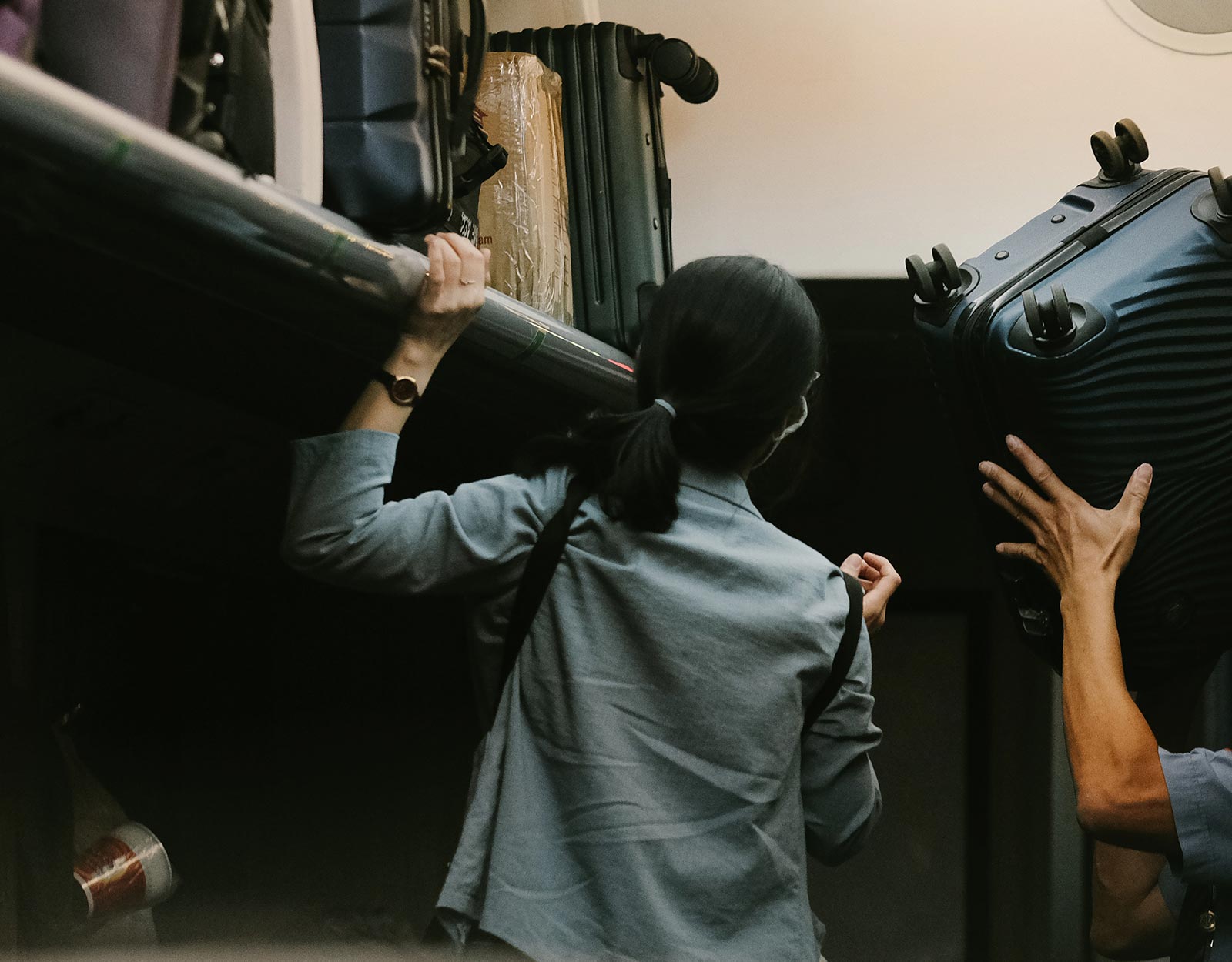 A woman putting her bag in the overhead bin