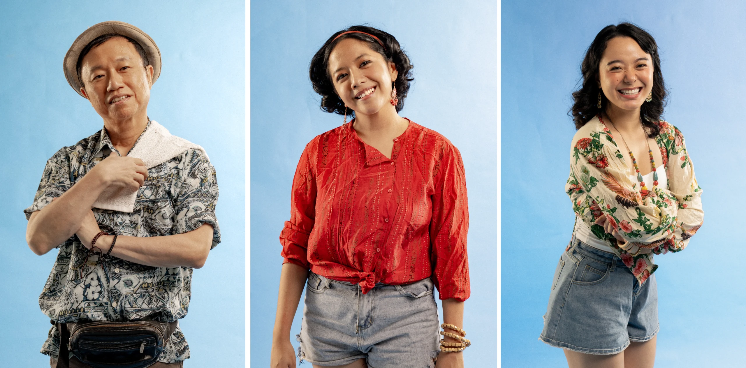 Three people pose against a blue backdrop: a man on the left wearing a hat and patterned shirt, a woman center in a red blouse, and a smiling woman on the right in a floral top.