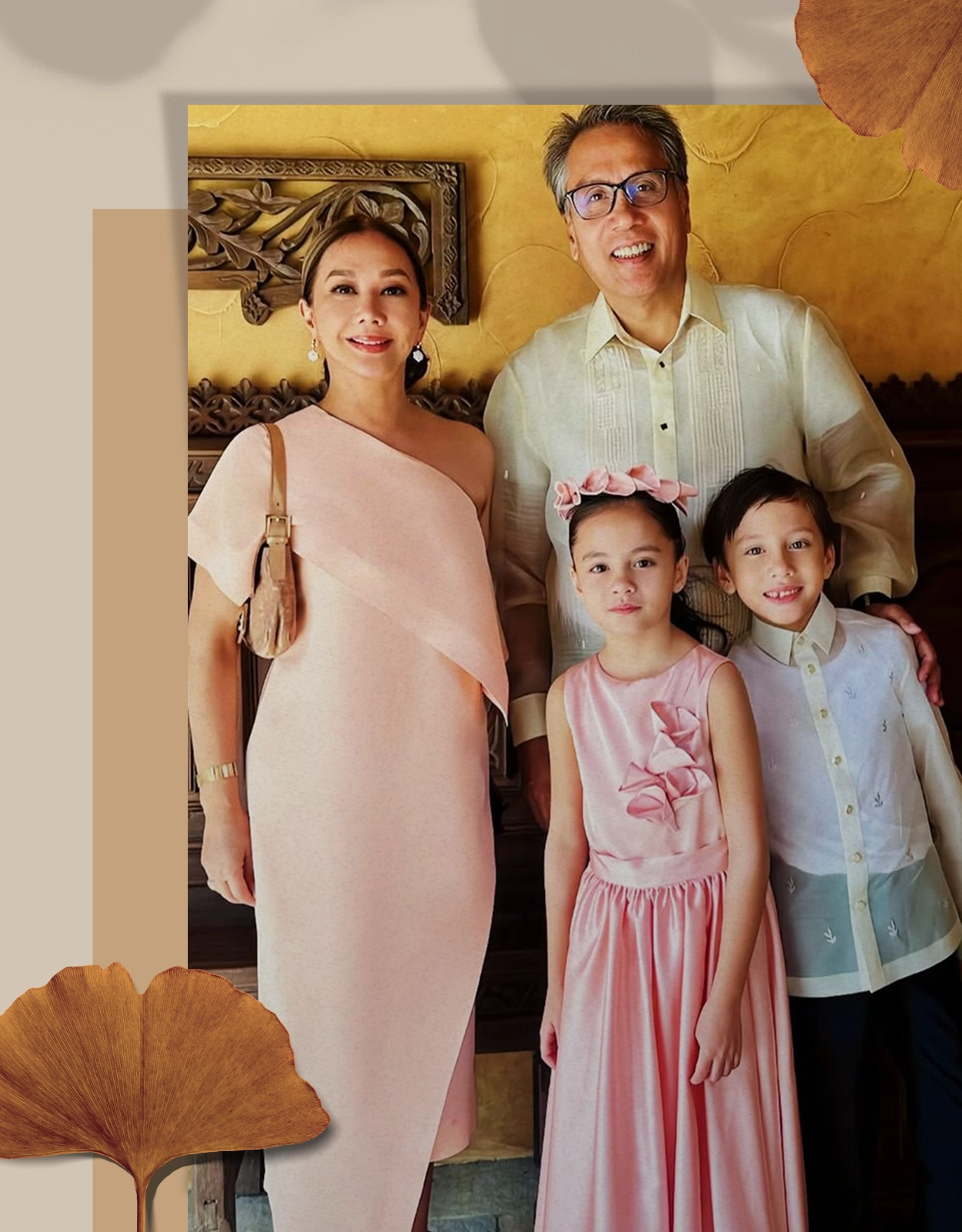 Family of four posing for a portrait: mom in a pink one-shoulder dress, dad in a light button-down shirt, daughter in a pink dress with a flower headband, and son in a white shirt with pastel accents.